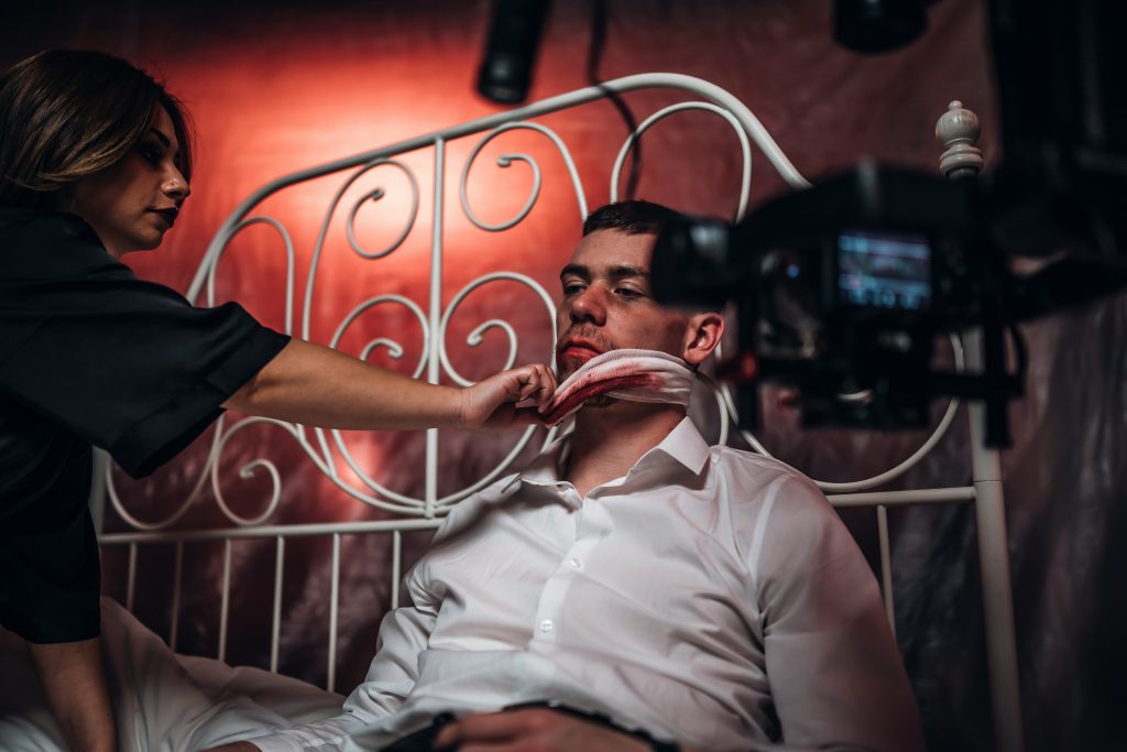 カメラの前で俳優がベッドで横たわりスタンバイしている画像